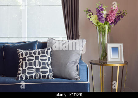 Bleu marine canapé classique moderne et rétro, oreillers gris et bleu avec un beau vase d'orchidées sur table de nuit dans le coin séjour Banque D'Images