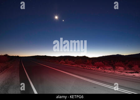 En regardant un tronçon de route droit la nuit dans Joshua Tree National Park, Californie, États-Unis Banque D'Images