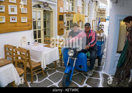 Ancien homme de la région de la conduite sur tricycle sur ruelle étroite du mykonos-ville, Mykonos, Grèce Banque D'Images