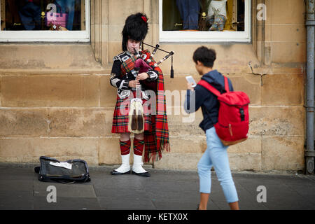 Performance de rue pour les touristes busker Edimbourg, Ecosse, le Royal Mile Canongate un traditionnel habillé piper jouant sa cornemuse pour l'argent Banque D'Images