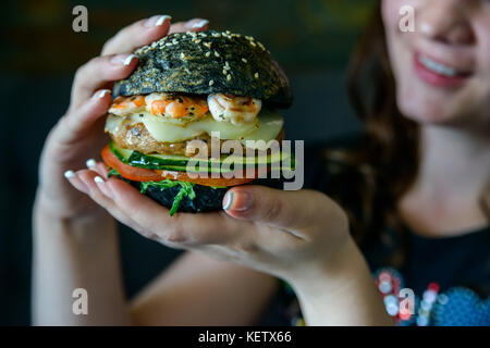 Close up young woman sitting at table de restaurant avec burger Banque D'Images
