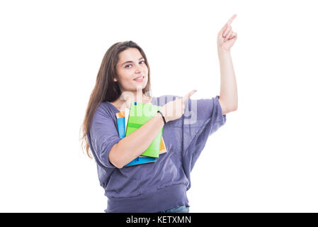 Smiling student girl holding books et pointant vers le haut sur fond blanc Banque D'Images