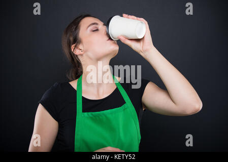 Belle brune dégustation vendeur un expresso frais dans son temps de pause isolé sur fond sombre Banque D'Images