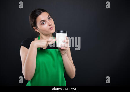 Un employé de supermarché attrayant café jetable sur fond sombre studio Banque D'Images