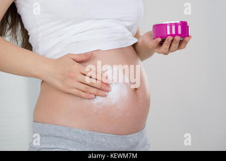 Close-up of pregnant woman applying cream sur son ventre Banque D'Images