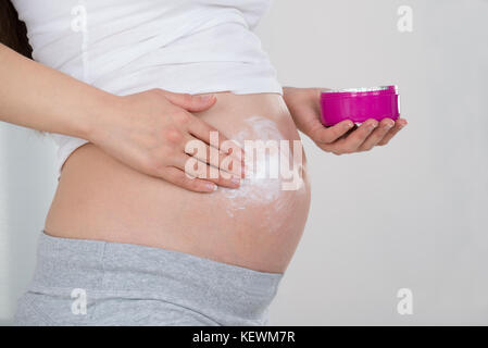 Close-up of pregnant woman applying cream sur son ventre Banque D'Images