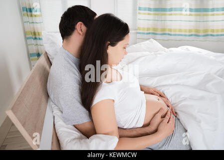Expecting couple sitting on sofa in living room Banque D'Images