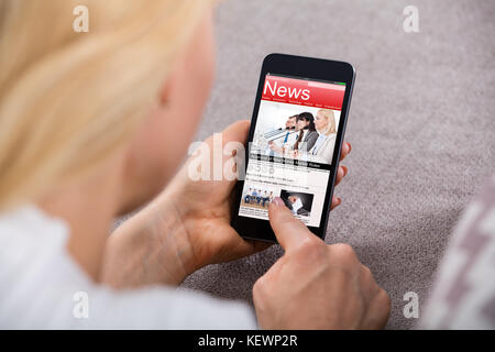 Close-up of a woman reading news on mobile phone Banque D'Images