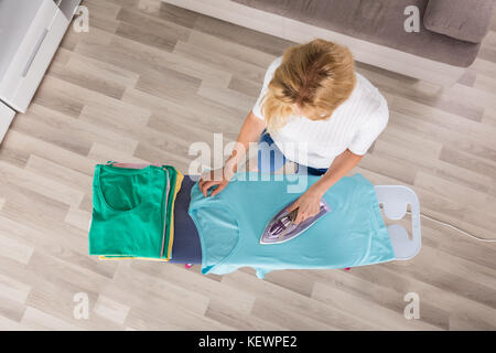 High angle view of woman ironing clothes sur planche à repasser à la maison Banque D'Images