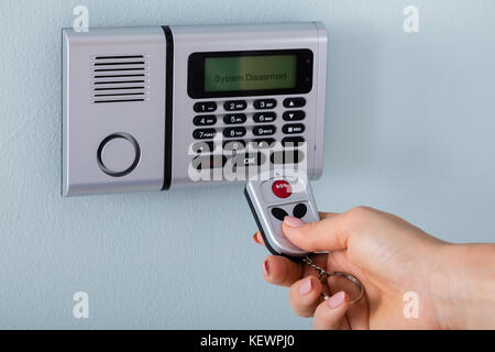 Personne de la main à l'aide de télécommande d'alarme de sécurité en face de Banque D'Images