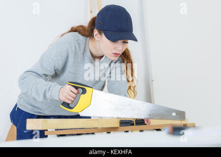 Jeune femme à l'aide d'une scie à main dans un atelier de Banque D'Images