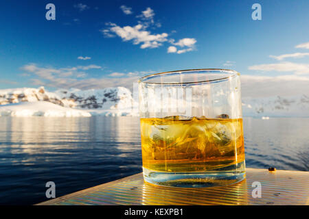 Un Scotch sur les rochers avec de la glace de glacier vieille de 100,000 ans sur le pont de l'Akademik Sergueï Vavilov, un navire renforcé de glace lors d'une croisière d'expédition en Antarctique, au large de la péninsule antarctique au détroit de Gerlache. La péninsule antarctique est l'un des endroits les plus rapidement réchauffés de la planète. Banque D'Images