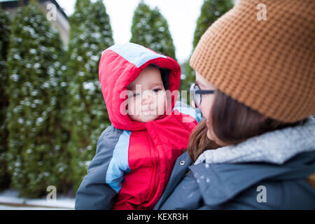 Mother holding baby à l'extérieur en hiver tout en portant des vêtements chauds, Langley, Colombie-Britannique, Canada Banque D'Images