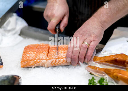 Poisson britannique monger le tranchage, filetage ou frais coupe slamon sur glace sur un marché personnel dans Yorkshire, Angleterre Banque D'Images