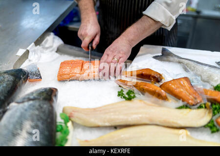 Poisson britannique monger le tranchage, filetage ou frais coupe slamon sur glace sur un marché personnel dans Yorkshire, Angleterre Banque D'Images