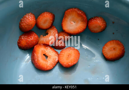Les fraises tranchées dans un bol bleu. Banque D'Images