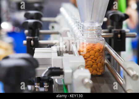 L'industrie pharmaceutique, de la médecine sont comprimés en remplissant la bouteille en plastique sur la ligne de production machine convoyeur à l'usine médicale. focus sélectif. Banque D'Images