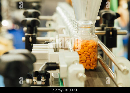 L'industrie pharmaceutique, de la médecine sont comprimés en remplissant la bouteille en plastique sur la ligne de production machine convoyeur à l'usine médicale. focus sélectif. Banque D'Images