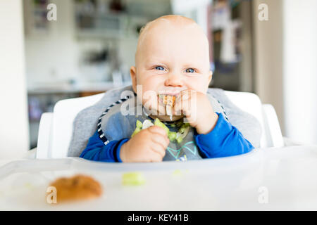 Baby eating bread et concombre avec méthode, BLW led bébé sevrage. Heureux végétariens kid au dîner. Tout-petit manger lui-même, auto-alimentent. Banque D'Images