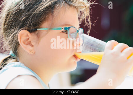 Portrait d'une jolie fille enfant holding glass avec de délicieux jus d'orange. mode de vie sain, régime végétarien et repas. verre de jus. soins de santé et de beaut Banque D'Images