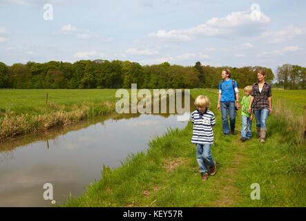 Famille de quatre jeunes à marcher ensemble le long d'un petit ruisseau Banque D'Images