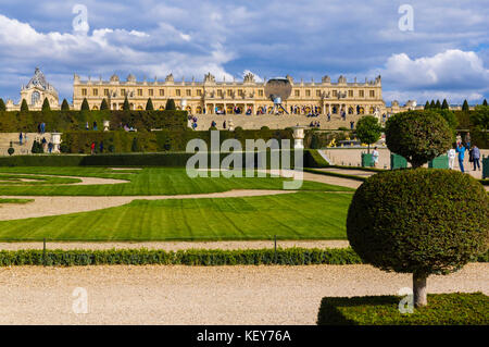 Jardins du Château de Versailles, dans l'art topiaire et le palais en premier plan l'arrière-plan sur un fond bleu ciel nuageux. En face du palais est l'installation d'art 2015, 'ciel', en miroir de l'artiste contemporain britannique Anish Kapoor. Banque D'Images