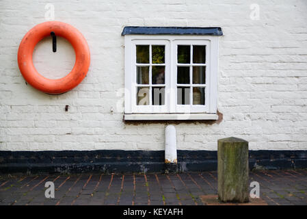 Côté canal cottage avec fenêtre et anneau de sauvetage sur le mur blanc Banque D'Images