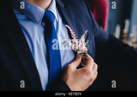 Matin, marié Marié dans une veste, le marié se redresse la boutonnière, jour de mariage Banque D'Images