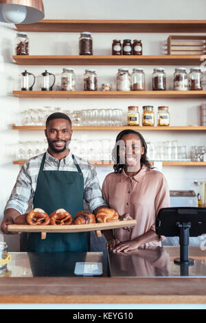 Deux propriétaires de boulangerie smiling african debout derrière leur comptoir Banque D'Images