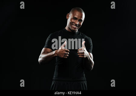 Portrait of a young man smiling african sports, showing Thumbs up isolé sur fond noir Banque D'Images