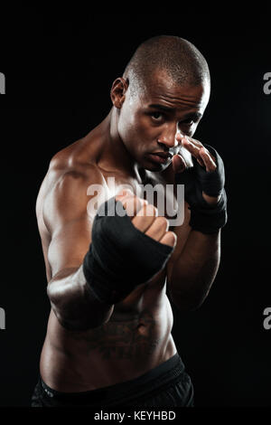 Portrait de afroamerican posant en boxer boxing bandage sur fond noir, prêts à se battre Banque D'Images