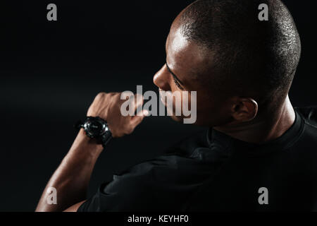 Image Gros plan homme de jeunes vêtus de t-shirt noir debout sur fond noir l Banque D'Images