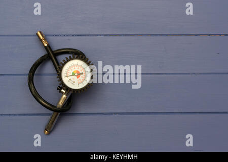 Gonflage des pneus à manomètre de pression d'air sur les planches de bois bleu Banque D'Images