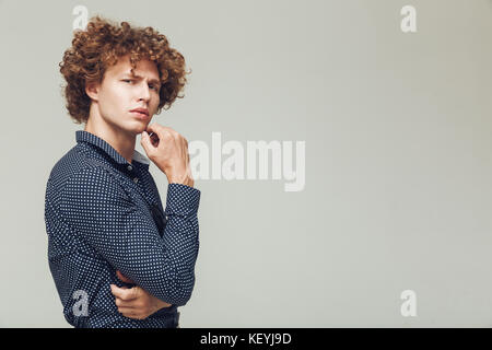 Image de sérieux jeune homme habillé en retro shirt debout et posant isolé. À la caméra. Banque D'Images