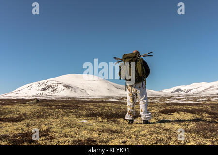 Randonneur avec grand sac à dos marchant dans les montagnes d'hiver à Dovre, Norvège. Côté droit Banque D'Images