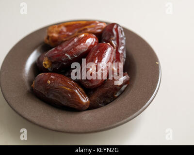 Fruits dates dans une assiette sur fond de bois, pour le ramadan Banque D'Images