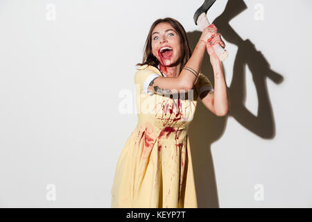 Screaming Mad zombie femme en tenue d'attaquer avec une hache et regardant la caméra sur fond blanc Banque D'Images