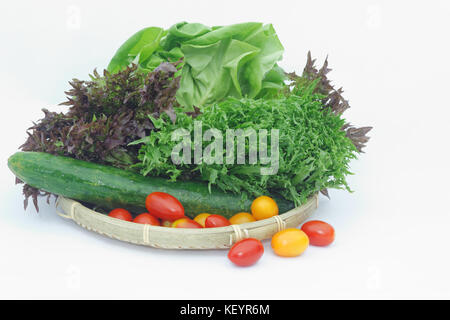 Les légumes tels que les tomates cerises, concombre, amd japon rouge vert laitue lollo et la laitue dans un bac en osier isolé sur fond blanc Banque D'Images