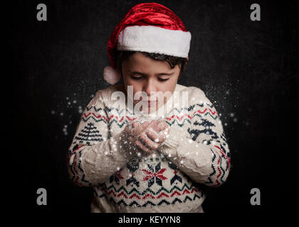 Petit enfant souffle la neige de Noël dans les mains Banque D'Images