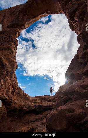 En femme debout dans la tourelle du rétroéclairage arch dans le Arches national park, Utah, USA Banque D'Images