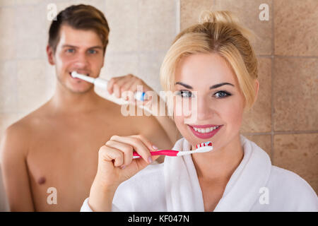 Portrait de l'homme et de la femme se brosser les dents dans la salle de bains à la maison Banque D'Images