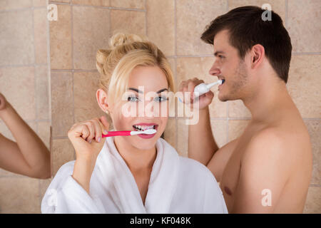 Portrait de l'homme et de la femme se brosser les dents dans la salle de bains à la maison Banque D'Images