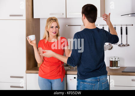 Jeune couple ayant querelle sur le divorce et l'infidélité dans la cuisine à la maison Banque D'Images