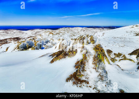 Des roches couvertes de mousse sur le dessus du mont Perisher Retour haut dans les montagnes enneigées du parc national de Kosciuszko, NSW, Australie, pendant la saison d'hiver. Banque D'Images