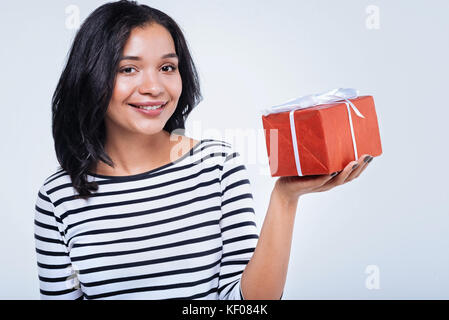 Cheerful young woman holding gift box sur sa paume Banque D'Images