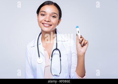 Charmante femme médecin posant avec un thermomètre Banque D'Images