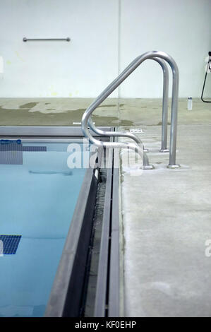 Mains courantes en métal incurvée sur étapes piscine vue sur le bord de la piscine et l'dallée Banque D'Images
