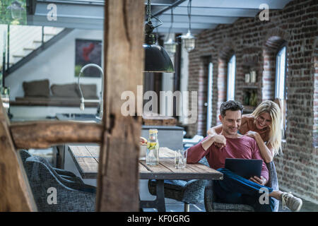 Couple heureux antennes en country house cuisine, looking at laptop Banque D'Images