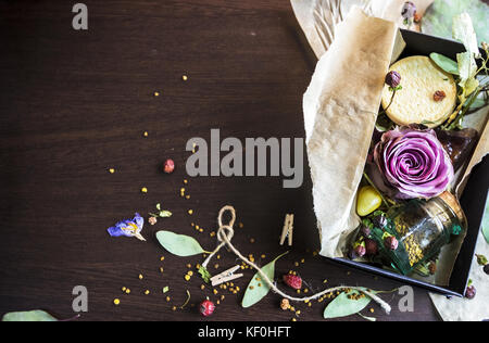 Rose en boîte noire avec une foule de petits détails sur fond de bois Banque D'Images