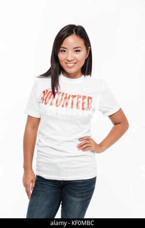 Portrait of a smiling asian woman in Casual t-shirt et permanent à la caméra au plus isolé sur fond blanc Banque D'Images